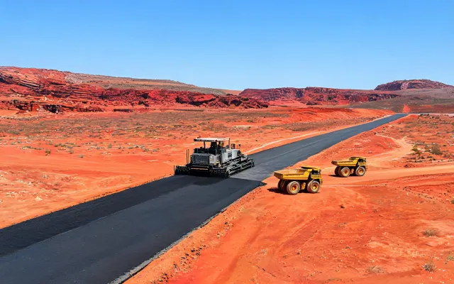 Paver laying haul-road asphalt in red iron-ore mining region