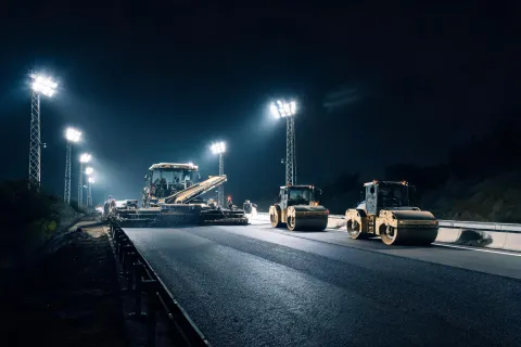 Highway night paving train under floodlights